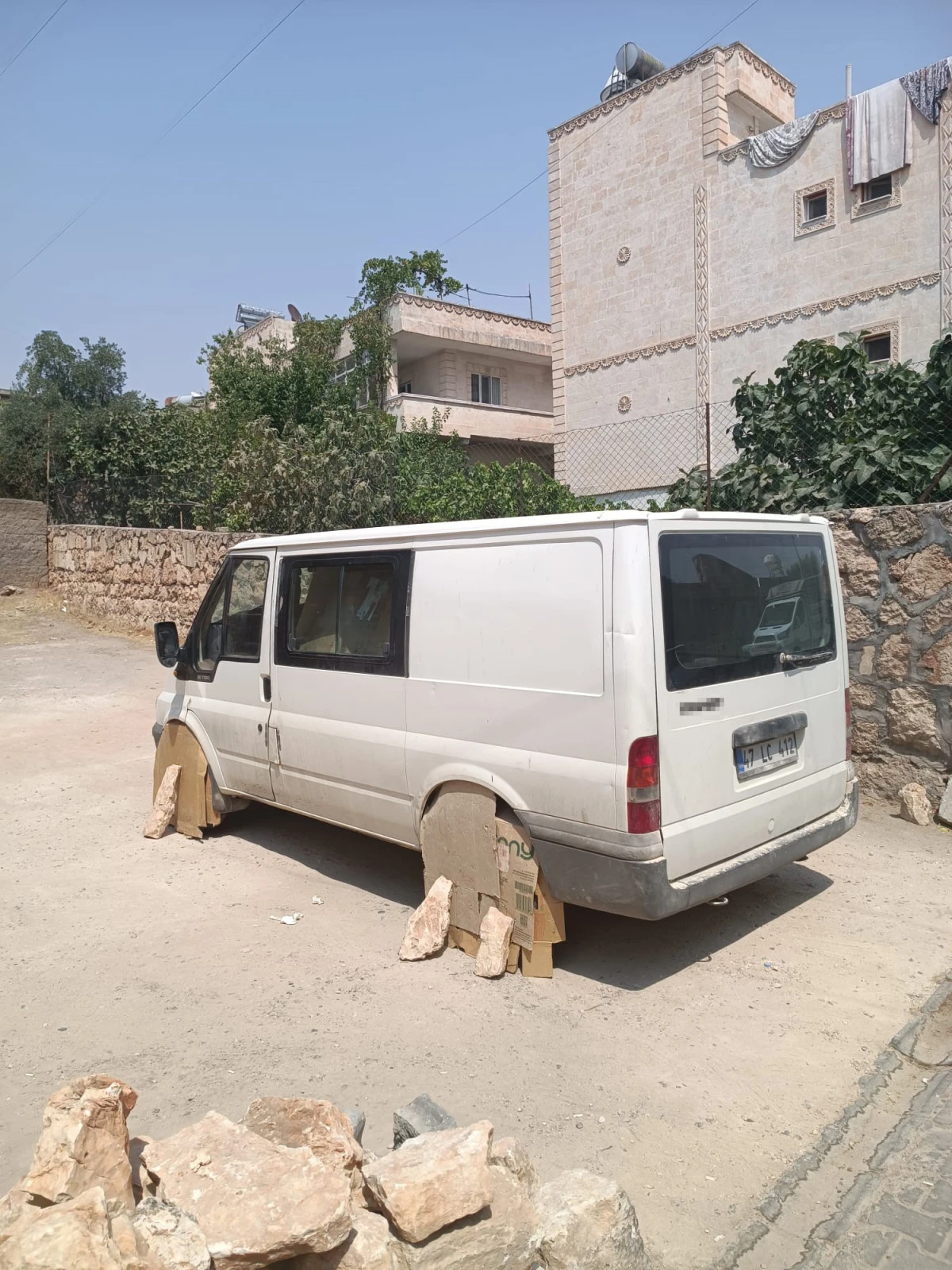 Mardin'de minibüs sürücüsü, aracın tekerlerini sıcaktan korumak için kartonla kapattı